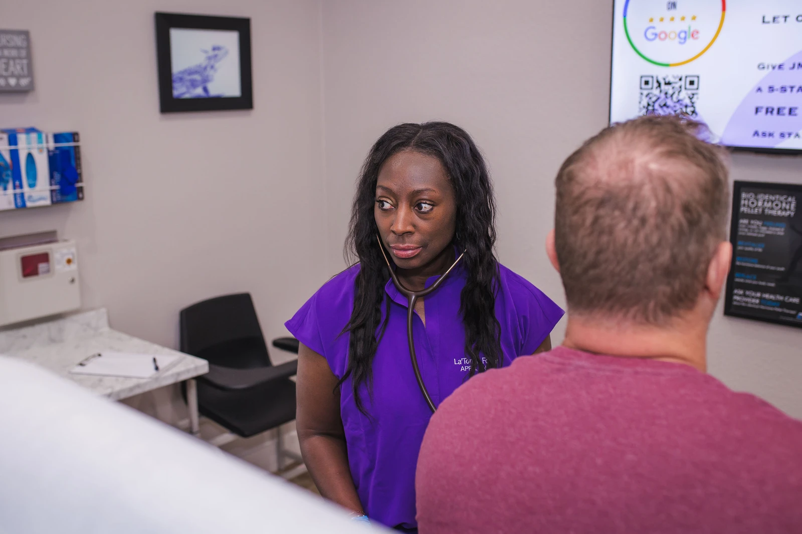 A JM Wellness provider examining a patient with a stethoscope