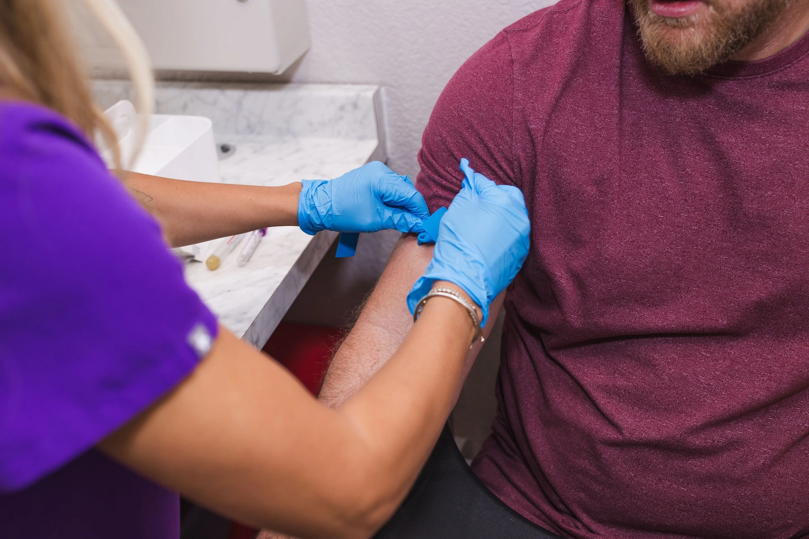 A JM Wellness staff member preparing a patient’s arm for lab work